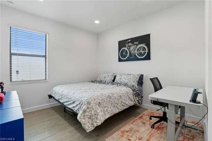 Bedroom featuring wood tiled floors, recessed lighting, and an office area