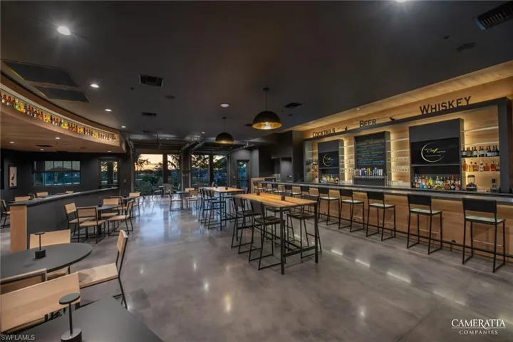 Bar area with finished concrete floors, hanging light fixtures, dark countertops, and recessed lighting