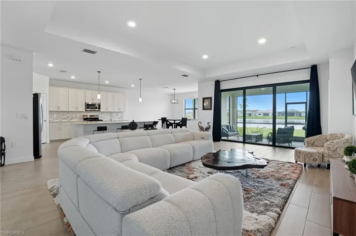 Living room featuring recessed lighting, a tray ceiling, and light wood-type flooring