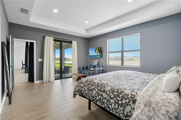 Bedroom with a raised ceiling, multiple windows, access to exterior, and recessed lighting