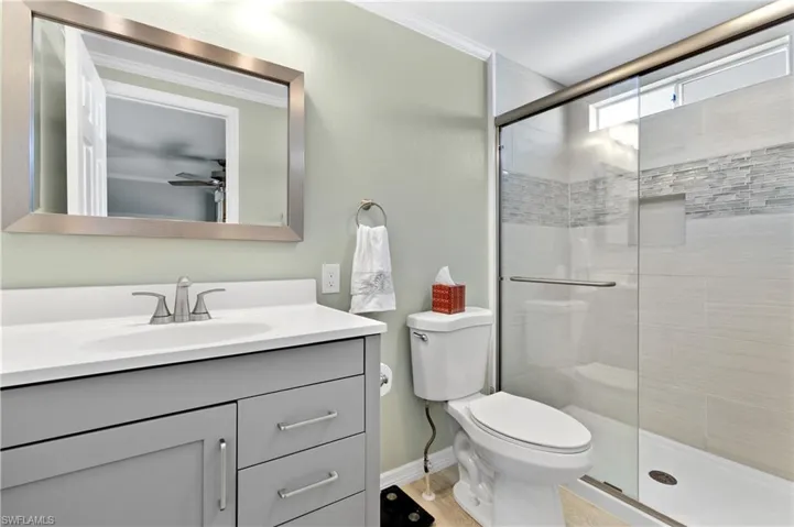 Full bathroom with vanity, a shower stall, crown molding, and ceiling fan