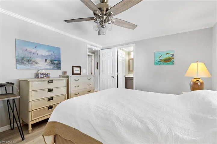 Bedroom with light wood-style flooring, ornamental molding, a ceiling fan, and connected bathroom