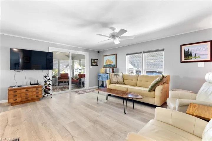 Living area with healthy amount of natural light, ornamental molding, wood finished floors, and a ceiling fan