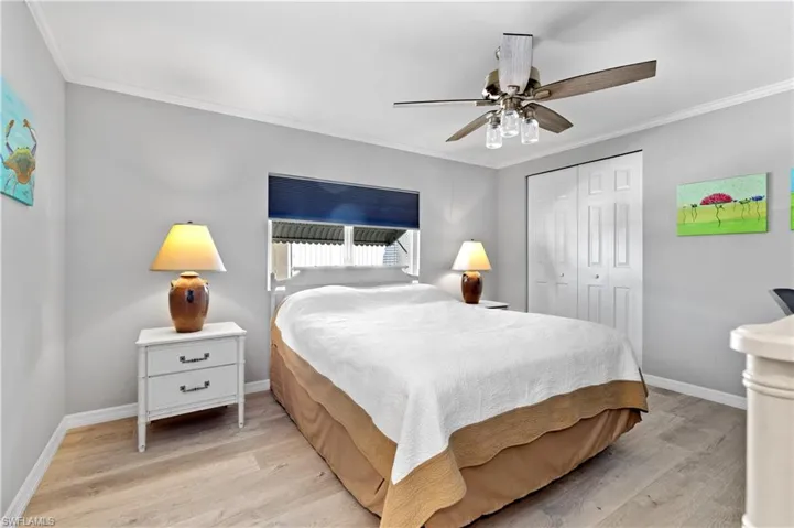 Bedroom with light wood finished floors, a closet, crown molding, and a ceiling fan