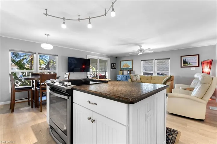 Kitchen featuring stainless steel electric range, white cabinets, a center island, dark countertops, and light wood-style floors