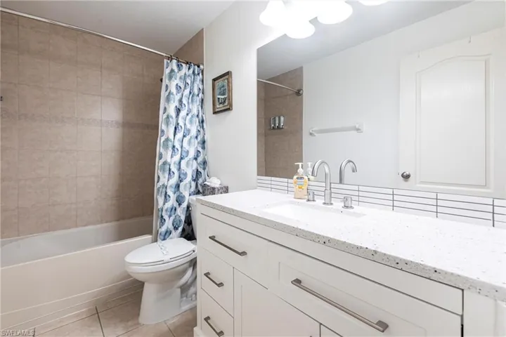 Full bath with vanity, shower / bath combination with curtain, and light tile patterned floors