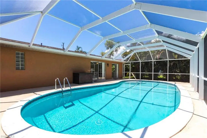 Swimming pool featuring a patio area, a sunroom, and glass enclosure