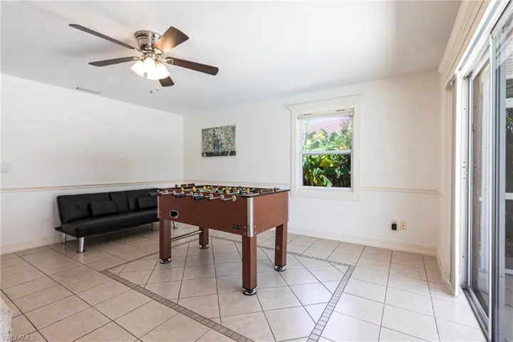 Recreation room with light tile patterned floors, inlaid floor details, and ceiling fan