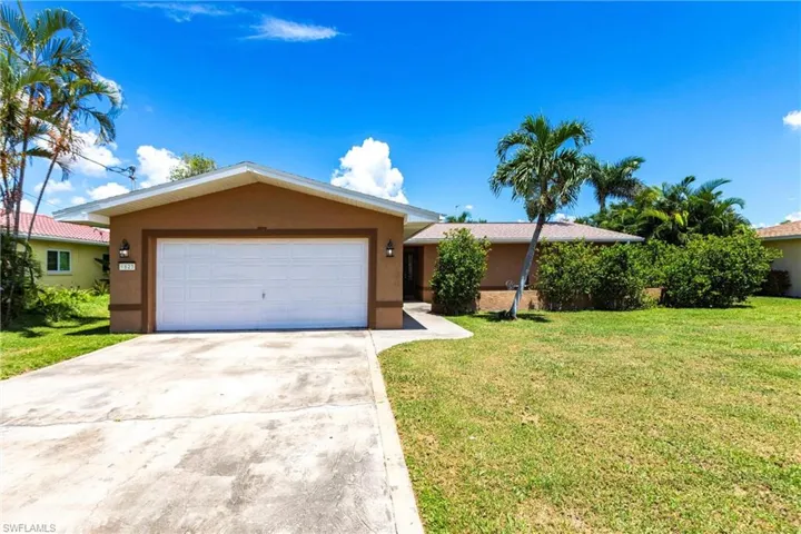 Ranch-style house with stucco siding, driveway, a front yard, and a garage