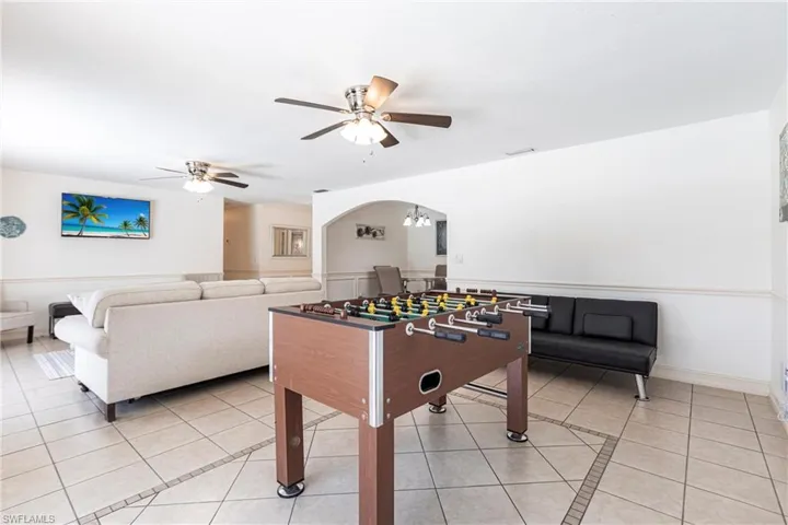 Playroom with light tile patterned floors, a ceiling fan, arched walkways, and inlaid floor details