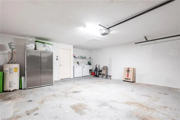 Garage with independent washer and dryer, water heater, and a garage door opener