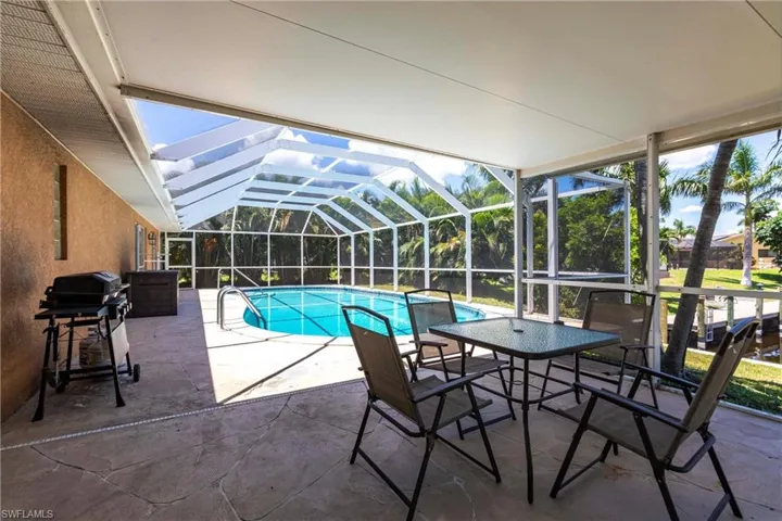 Outdoor pool featuring glass enclosure, a patio area, area for grilling, and a sunroom