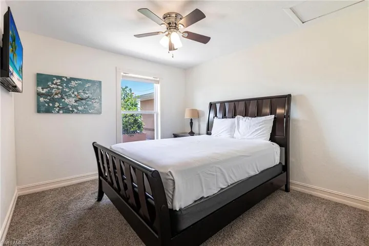 Bedroom with a ceiling fan and dark colored carpet
