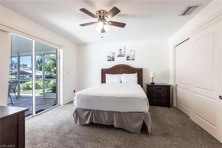 Carpeted bedroom with a closet, access to exterior, and a ceiling fan