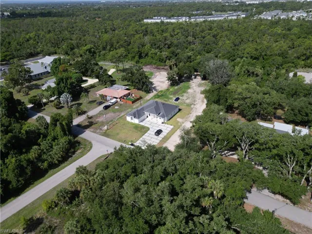 Aerial perspective showcasing a single-story residence with a dark-pitched roof and a light-colored exterior