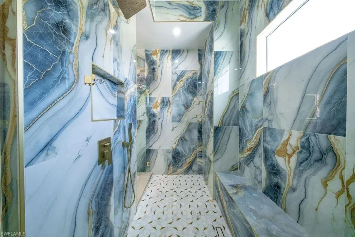Walk-in shower with full-height patterned tile, a built-in bench, and a rectangular transom window