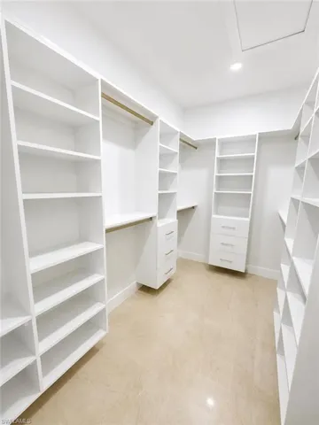 Custom closet organization system featuring white shelving, hanging rods, and built-in drawers
