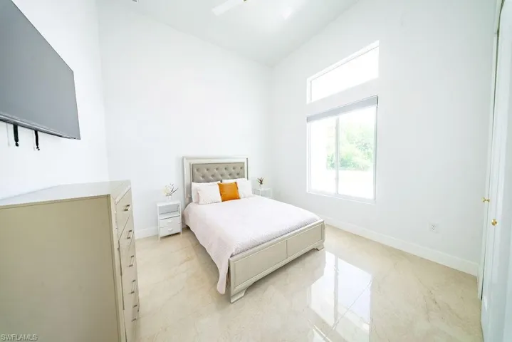 Bright room featuring vaulted ceilings, a large window with an additional transom window, and light-toned tile flooring