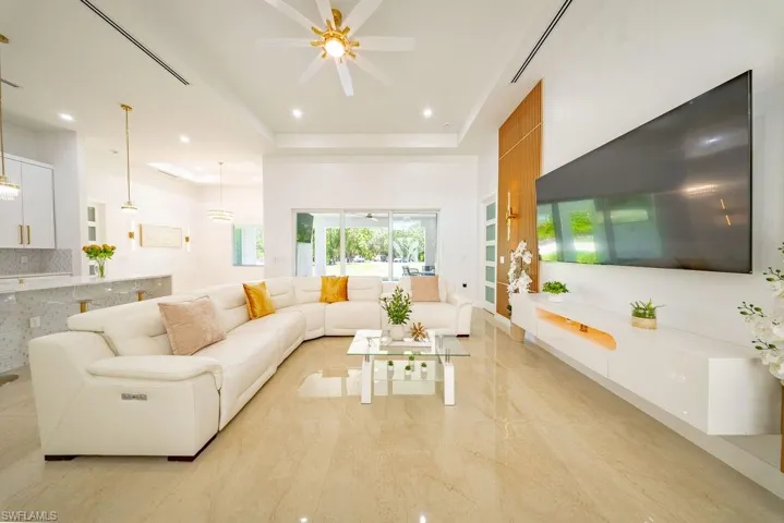 Spacious living area featuring polished tile flooring, a vaulted ceiling with a decorative ceiling fan, and recessed lighting
