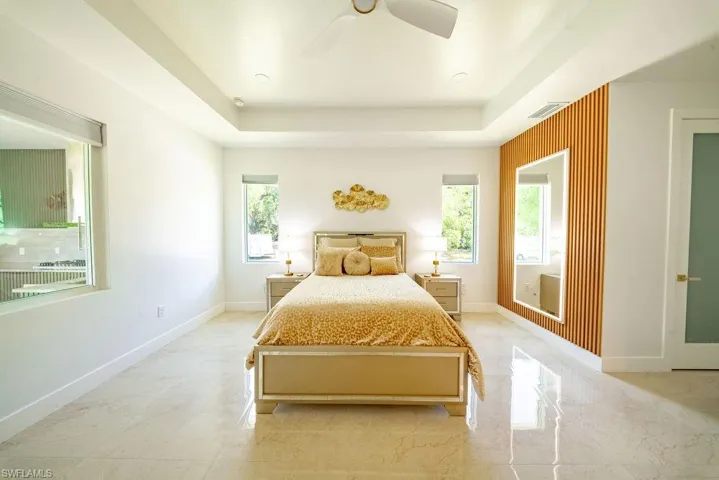 Spacious bedroom featuring a tray ceiling, recessed lighting, and a modern ceiling fan