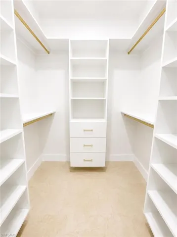 Custom white built-in closet system featuring shelving, hanging rods, and a central dresser unit with three drawers