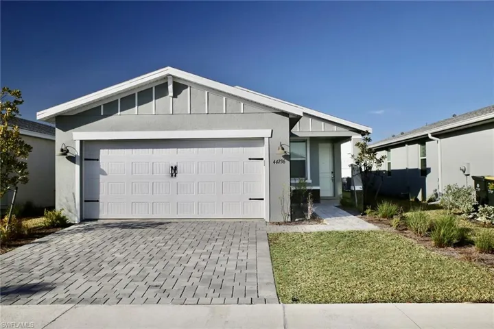 Ranch-style home featuring decorative driveway, an attached garage, board and batten siding, and stucco siding