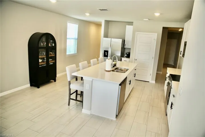 Kitchen featuring a kitchen bar, white cabinetry, a kitchen island with sink, stainless steel appliances, and recessed lighting