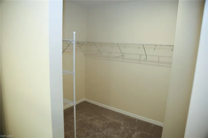 Walk in closet featuring dark colored carpet