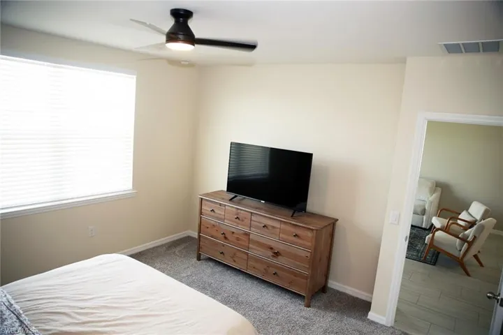 Carpeted bedroom featuring a ceiling fan and baseboards
