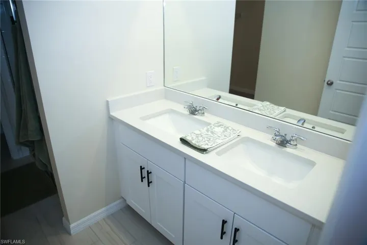 Full bathroom featuring double vanity and baseboards