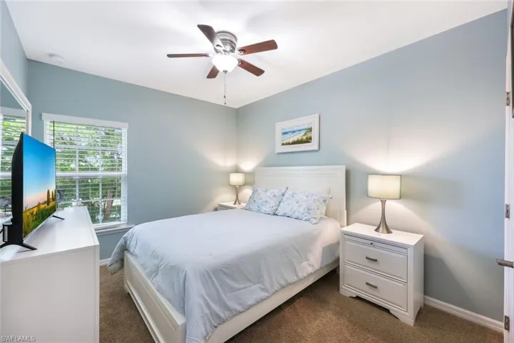 Bedroom featuring multiple windows, ceiling fan, and dark carpet