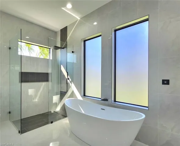 Full bathroom featuring tile walls, a freestanding tub, and walk in shower