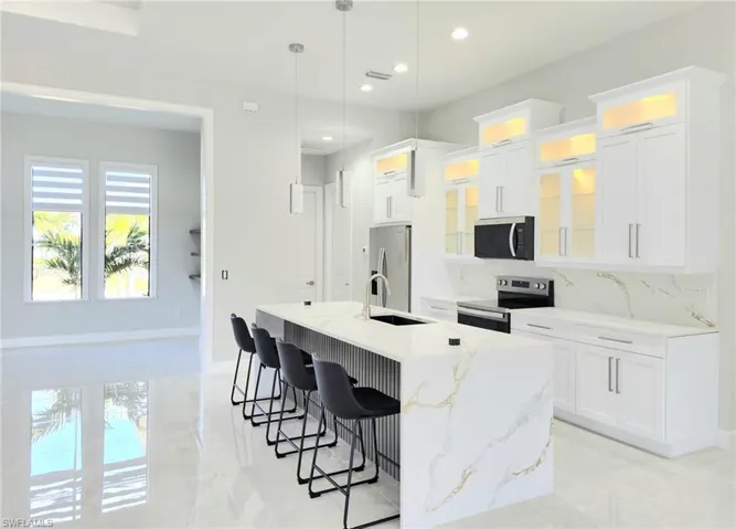 Kitchen featuring a kitchen breakfast bar, recessed lighting, an island with sink, appliances with stainless steel finishes, and a sink