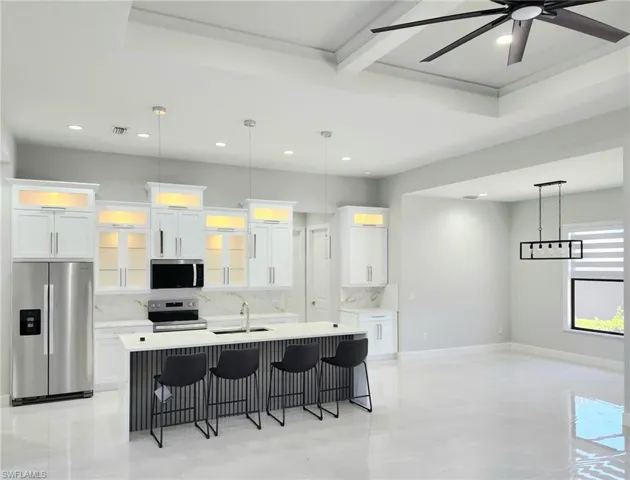 Kitchen with visible vents, appliances with stainless steel finishes, a kitchen bar, a center island with sink, and decorative backsplash
