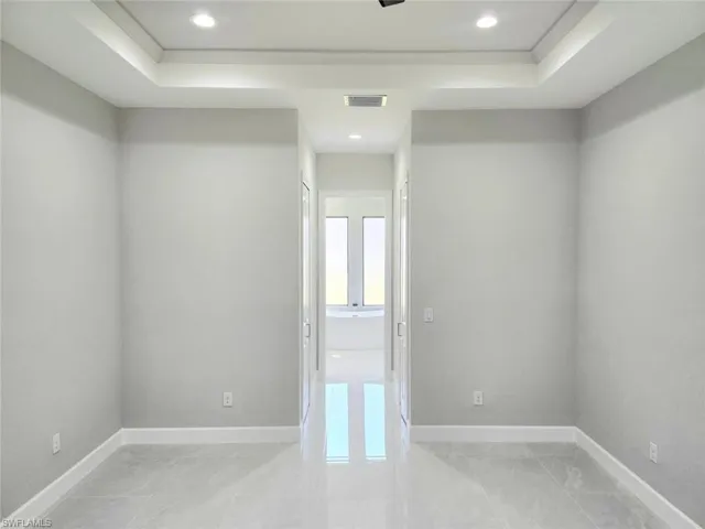 Unfurnished room featuring recessed lighting, visible vents, a tray ceiling, and baseboards