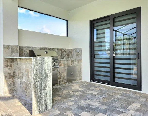 Property entrance featuring an outdoor kitchen, a sink, stone siding, and stucco siding