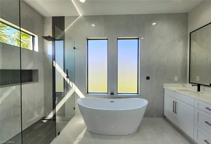 Full bath with tile walls, a walk in shower, a freestanding tub, and vanity