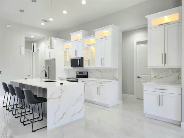 Kitchen featuring backsplash, appliances with stainless steel finishes, a breakfast bar, and recessed lighting