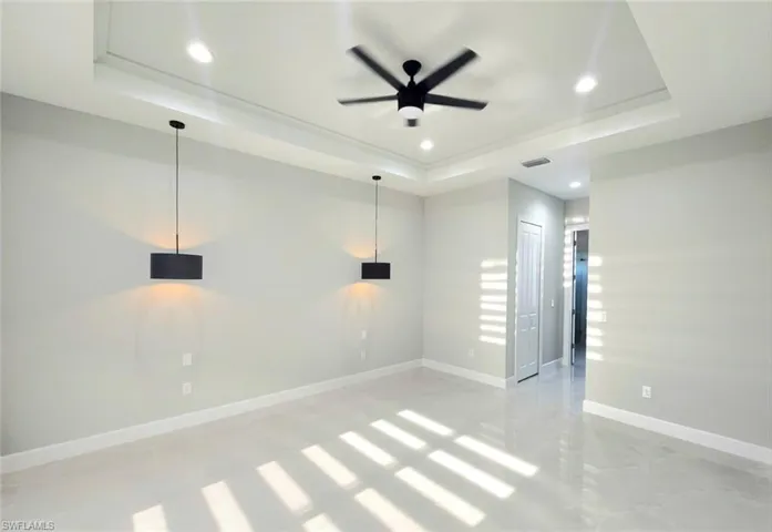 Spare room with visible vents, baseboards, a ceiling fan, a tray ceiling, and recessed lighting