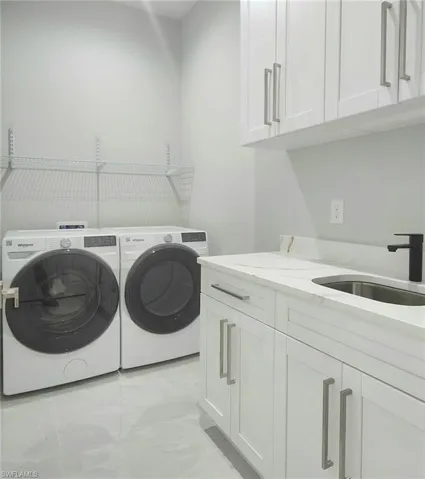 Laundry area featuring a sink, independent washer and dryer, cabinet space, and marble finish floor