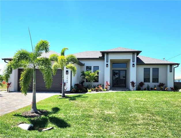 View of front of house with a garage, stucco siding, a front lawn, and decorative driveway