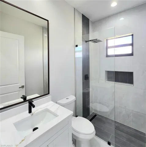 Bathroom with a walk in shower, vanity, and toilet