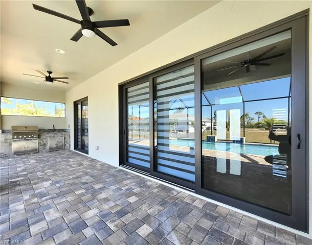 View of patio featuring area for grilling, ceiling fan, grilling area, an outdoor pool, and a lanai