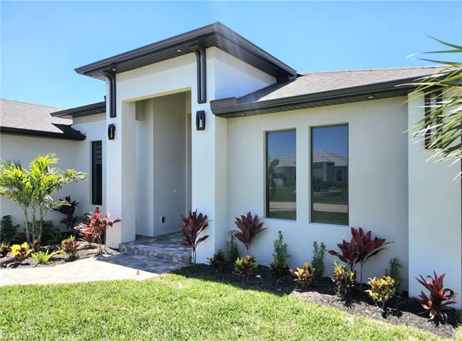 Doorway to property with a shingled roof and stucco siding