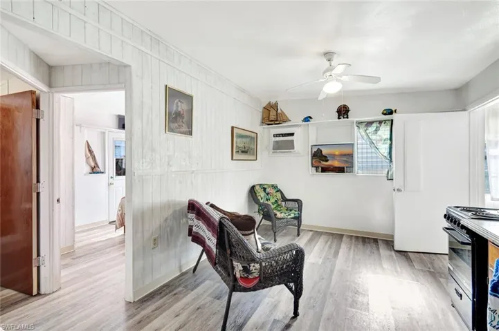 Sitting room featuring a ceiling fan, shelving, and light laminate flooring throughout.