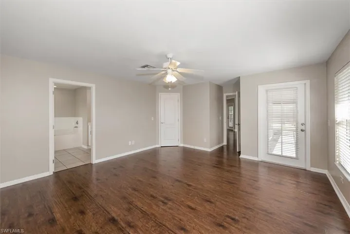 Unfurnished bedroom with a ceiling fan, dark wood-type flooring, and ensuite bath