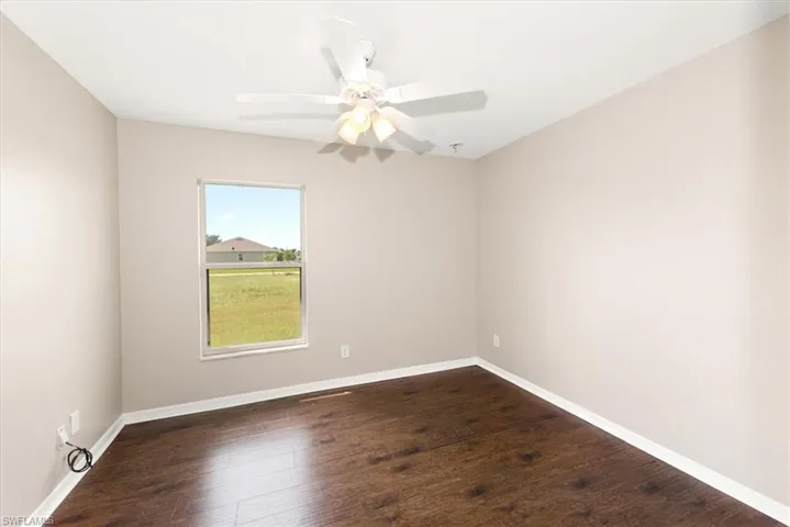 Unfurnished room with dark wood-style flooring and a ceiling fan
