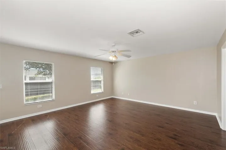Unfurnished room with dark wood-type flooring and a ceiling fan