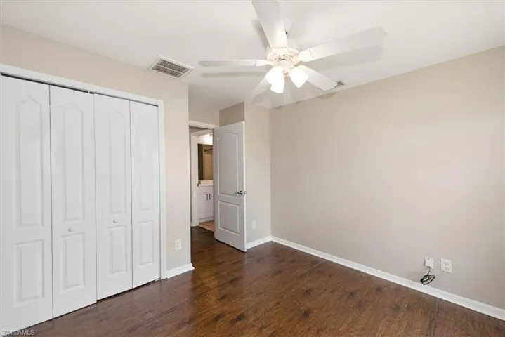 Unfurnished bedroom with dark wood-style floors, a closet, and ceiling fan