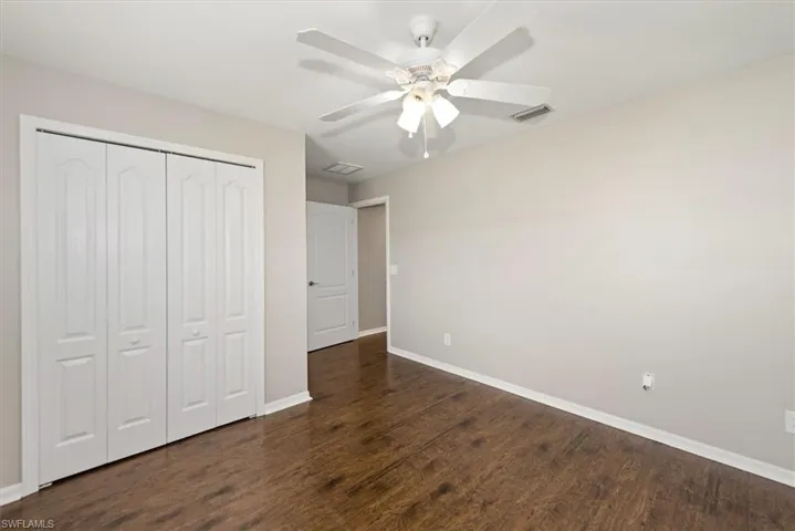 Unfurnished bedroom featuring dark wood finished floors, a closet, and ceiling fan